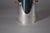 1980s metal wine cooler with a cylindrical silver-toned body, a textured decorative band around the lower section and two...