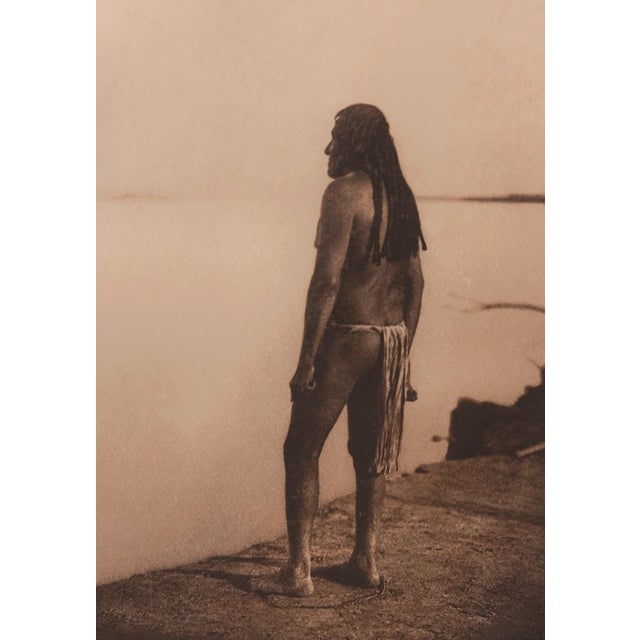 An original photogravure from Edward S. Curtis's The North American Indian. The Mohave shows a Mohave man standing on a...