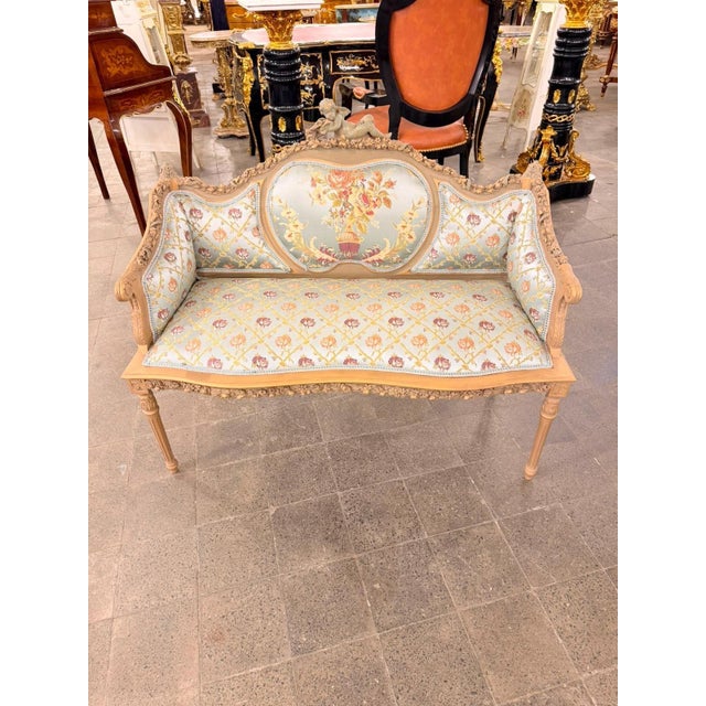 charming French Louis XVstyle canapé settee featuring a beautifully carved wood frame, soft floral upholstery, and a...