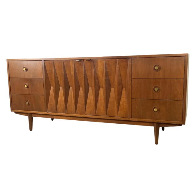 Exhibiting an extraordinary command of mid-century architectural rhythm, this vintage walnut triple dresser serves as a...