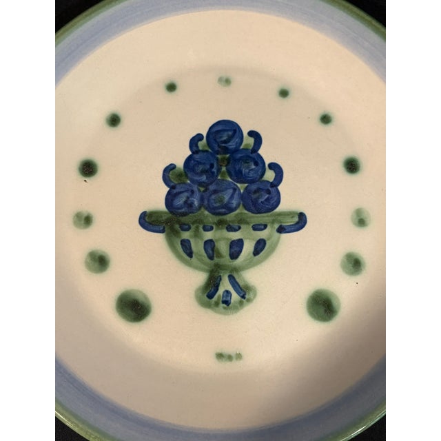 This vintage stoneware plate from M.A. Hadley features a hand-painted blue fruit/berry basket centerpiece surrounded by...