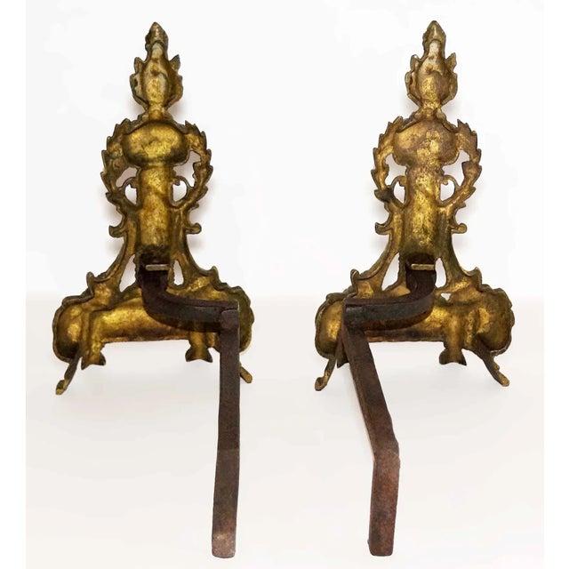 Antique early 20th century andirons having finely cast Neoclassical style decorative motifs. Cast iron with brass...
