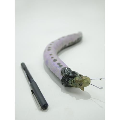 Curved ceramic sculpture depicting an anthropomorphic hybrid creature, combining human facial features with insect-like...