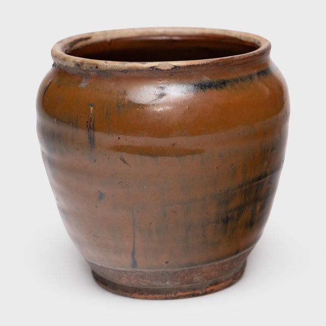 This antique Chinese jar from the early 20th century is cloaked inside and out with a beautiful drip glaze of warm brown...
