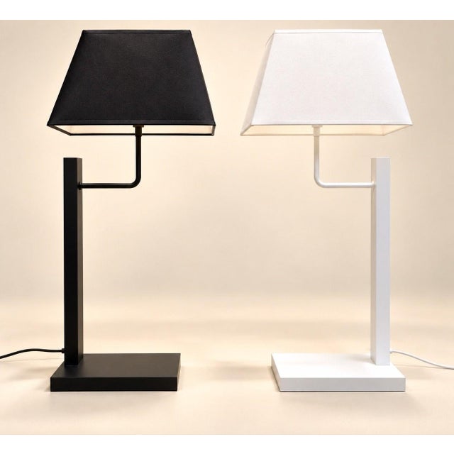 Each lamp rests on a flat, square, lacquered metal base, extended by a rectangular vertical stem and a right-angled arm...