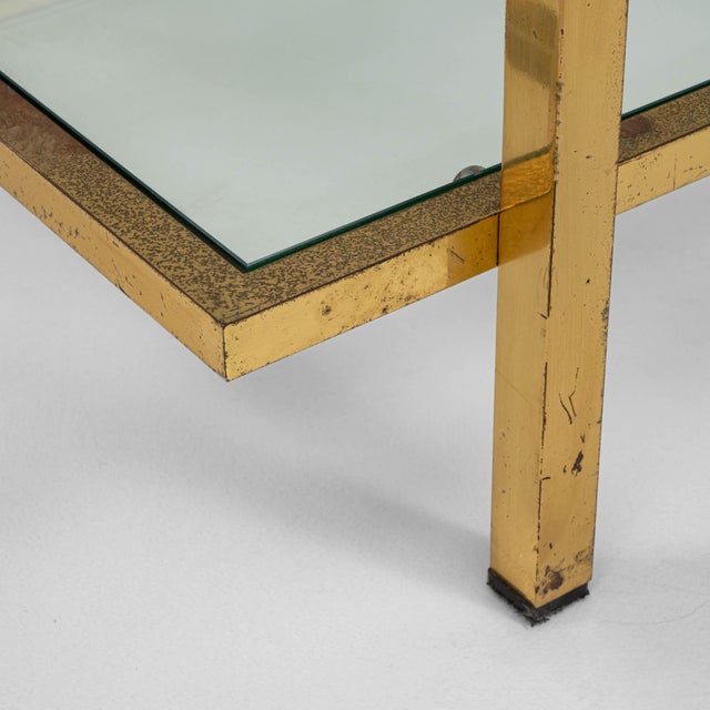 This 20th Century French coffee table features a sleek, rectilinear frame crafted from patinated brass, paired with two...
