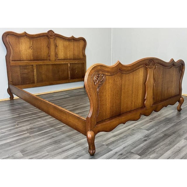 This Vintage French Louis double bed frame showcases elegant carved panels, flowing curves, and a warm oak wood finish...