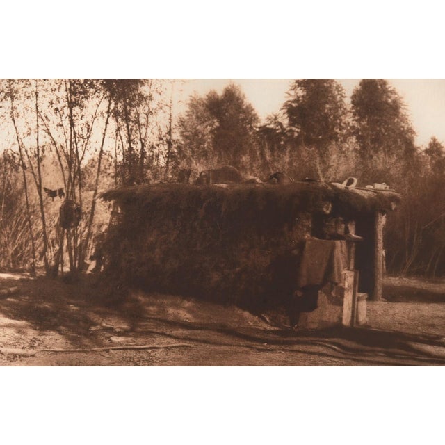 An original photogravure from Edward S. Curtis's The North American Indian. A Yuma House shows a low, brush-covered...