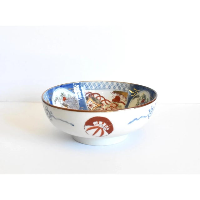 An antique, 19th-century Japanese Imari porcelain bowl with a smooth border and a primary design of rust red and...