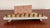 This well-designed menorah pairs a grey and rose cultured stone base with nine turned brass candle cups, the back panel...
