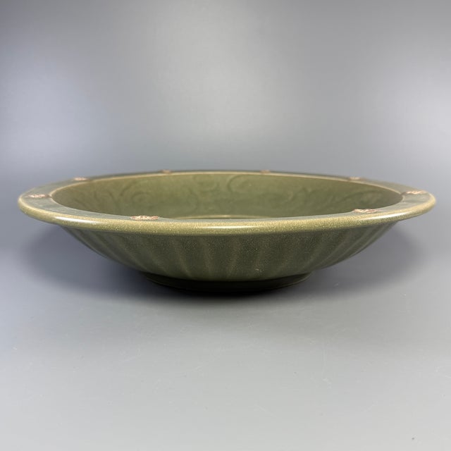 Fine antique Chinese celadon charger plate. Wide shallow form decorated with raised relief dragon motif at center, ribbed...
