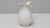 20th Century Belgian ceramic pitcher. This elegant white-glazed ceramic pitcher features a softly curved silhouette with a...