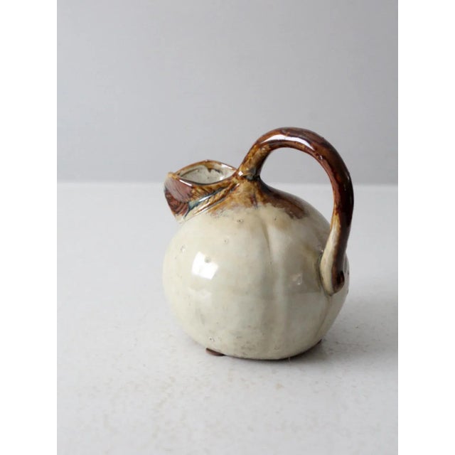This is a vintage studio pottery pitcher. The handmade ewer has a bulbous shape with leaf shaped spout.