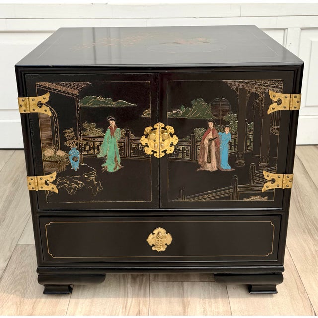 Here is a vintage Chinese Chinoiserie black lacquer nightstand, side cabinet dating to the mid-20th century. The cabinet...