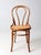 This vintage bentwood chair captures the elegance of Thonet-inspired design with its gracefully curved backrest, woven...