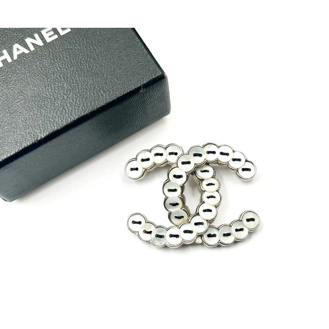 This is part of Chairish’s Costume Jewelry assortment. Chanel Rare Silver CC Mother of Pearl Button Brooch *Marked 08...