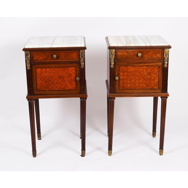 An elegant pair of antique french mahogany and ormolu mounted parquetry bedside chests, circa 1870 in date. The...