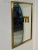 A sleek rectangular Italian wall mirror set within a wide brass frame, offering both strength and elegance. The warm...
