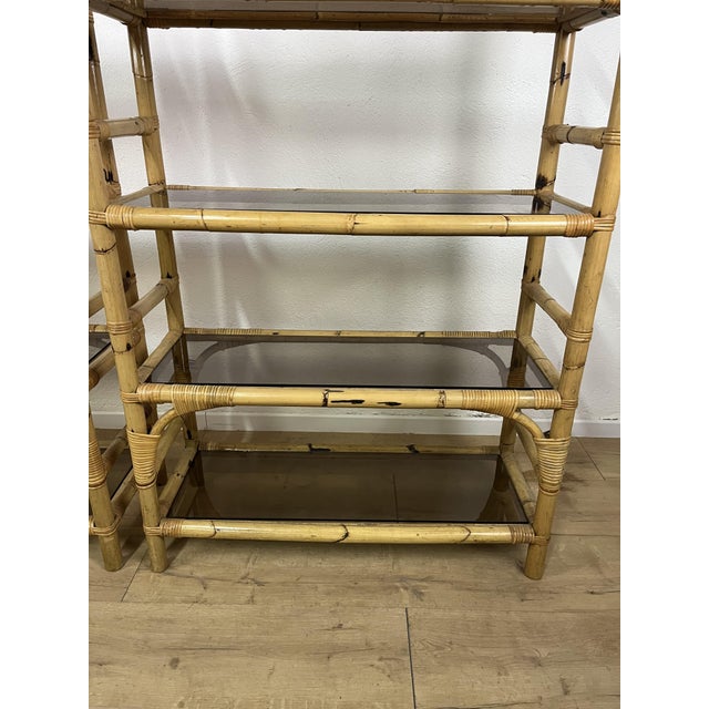 A pair of six-shelf bookcases with a bamboo frame, smoked glass shelves, and wicker details, made in Italy in the 1970s....