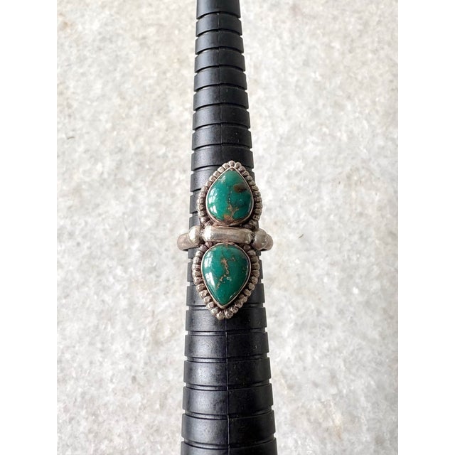 This sterling silver bohemian-style ring features two green-blue teardrop turquoise stones, resembling designs from...