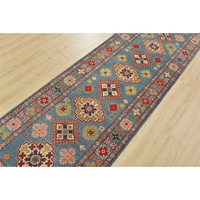 A tribal Caucasian Kazak runner hand-knotted with fine wool on a cotton foundation. This rug features a row of geometric...