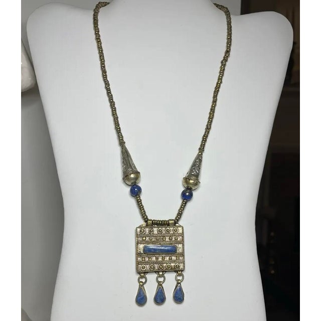 An early 20th-century Tibetan gau amulet box necklace crafted in silver alloy and richly accented with deep blue lapis...