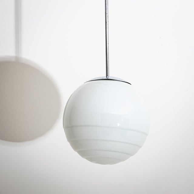 Pendant lamp made of chromed metal and frosted glass shade in the shape of a ball with three grooves. Up to 250V...