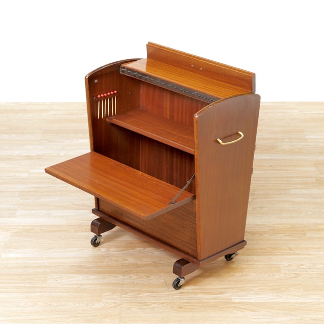 This fabulous mid century bar cart was manufactured in England during the 1960s. Produced in mahogany, this enclosed bar...