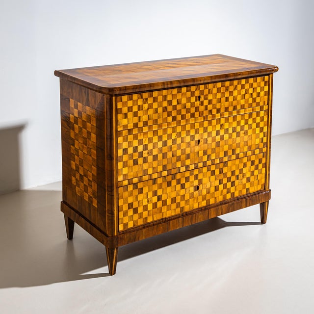 Three-drawer Biedermeier chest of drawers veneered in walnut and cherrywood, featuring an exceptional checkerboard pattern...