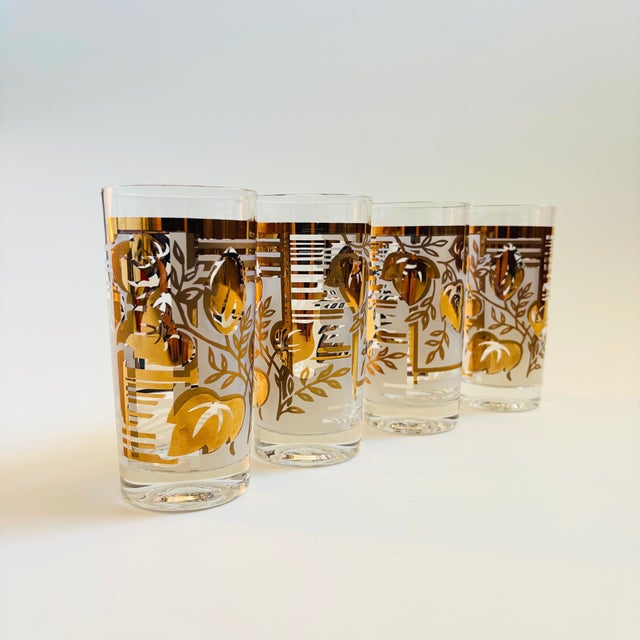 A set of 4 mid century highball tumblers. Each is decorated with a beautiful metallic gold leaf design.
