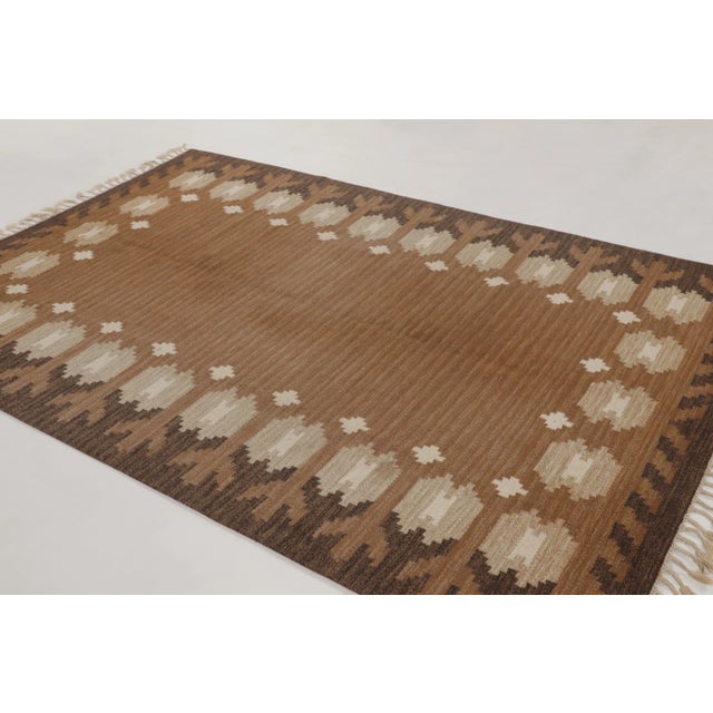 Hand-knotted in wool, this vintage 6x9 Swedish Deco Rollakan rug, dating circa 1950–1960 features a restrained geometric...