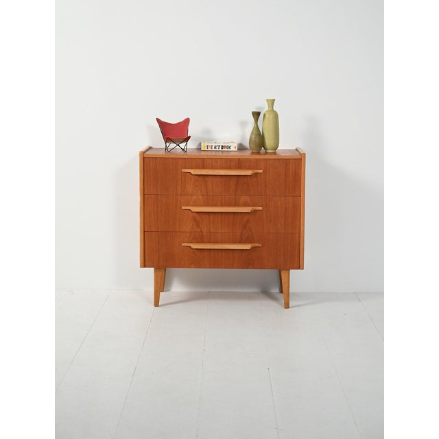 1950s-1960s chest of drawers with teak fronts, carved oak edges and handles, and flared legs. Compact, clean lines that...