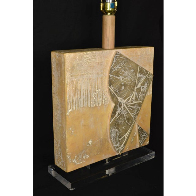 Large vintage table lamp with abstract art design carved in the coarse plaster square-shaped body. Lucite finial and base....