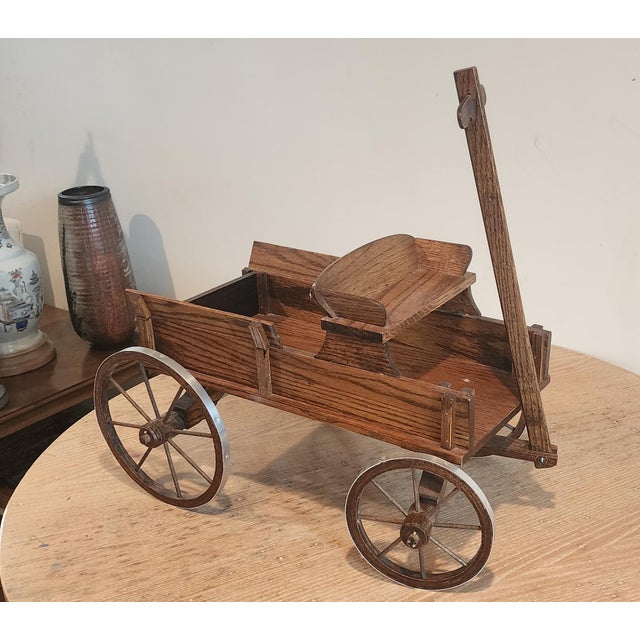 A late 20th century miniature handcrafted decorative oak wagon model with a raised bench seat, wooden spoked wheels and an...