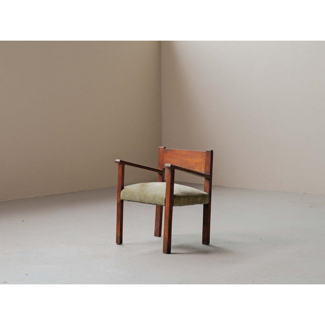 This solid wood armchair features an architectural structure resting on a straight base with clean, balanced lines. The...