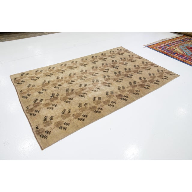 Beautiful antique Khotan hand-knotted wool rug with a Tan color field. This piece has a gorgeous floral pattern design...