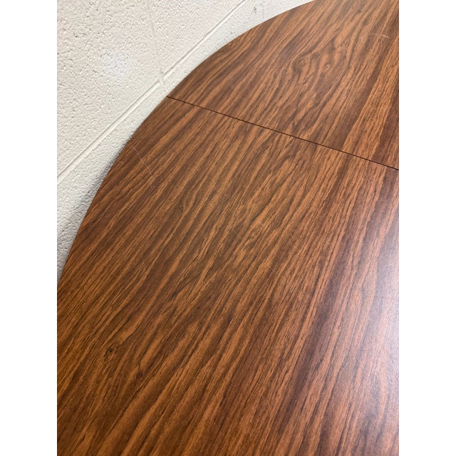 This is a vintage Mid Century Modern folding dining table featuring a richly figured rosewood-look laminate top with...
