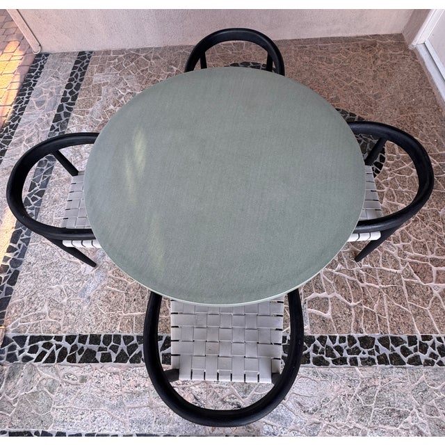 A refined and sculptural outdoor dining set featuring a round stone-top dining table by Four Hands, paired with solid teak...