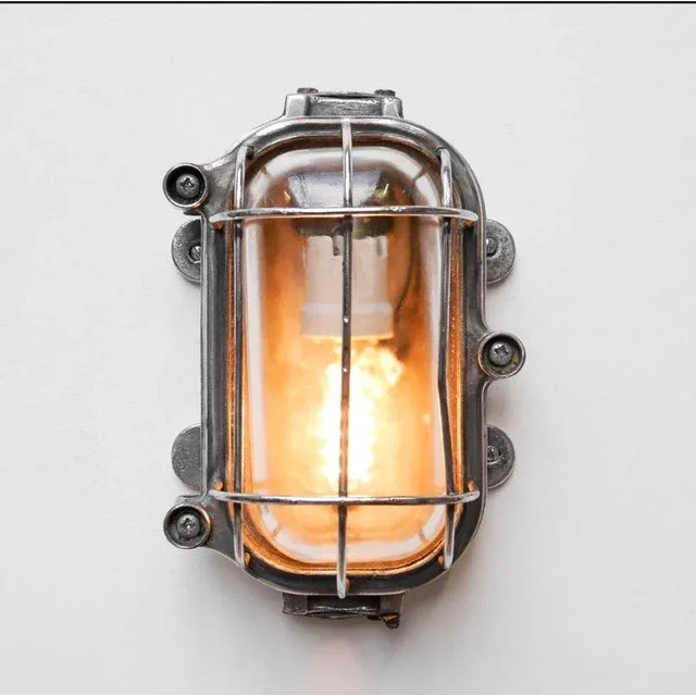 Old industrial outdoor wall lights, in cast aluminum, stripped, polished, with rounded mesh and transparent, thick and...