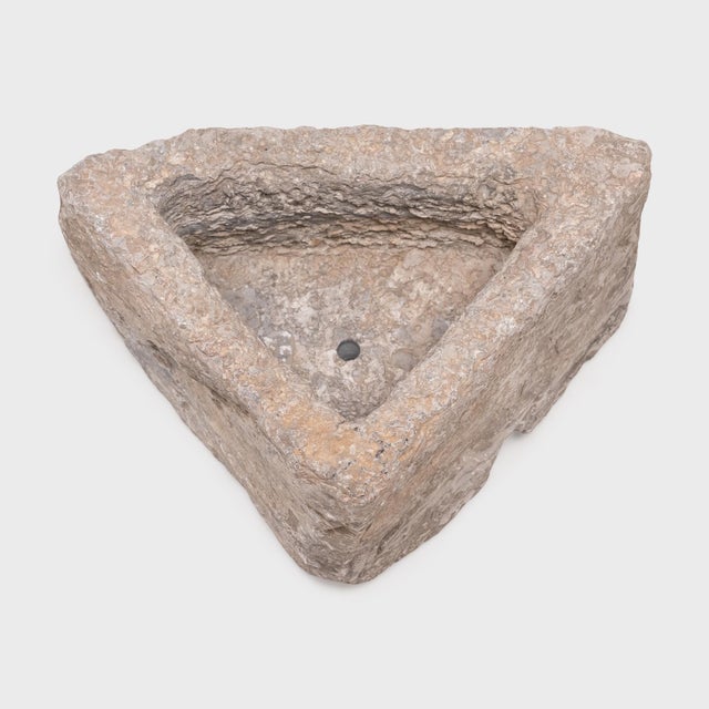 This small stone basin was carved by hand nearly two centuries ago, sculpted from solid limestone to an unusual triangular...