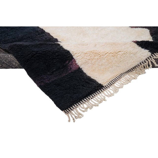 Light and shadow, cut into bold abstract form. This hand-knotted Moroccan wool rug plays with dramatic contrast — two...