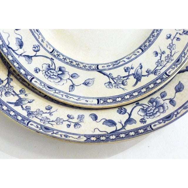 Two dishes (oval and round), in earthenware with white glaze, edge decorated with a blue printed decorative frieze...