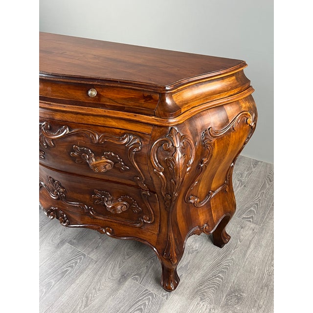 A louis xv style bombé commode in richly carved natural wood, featuring three drawers on the front. this elegant commode...