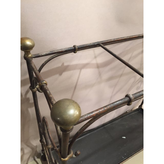 English painted iron umbrella with brass plated ball finial. Iron frame with scroll design and painted gilt accents.