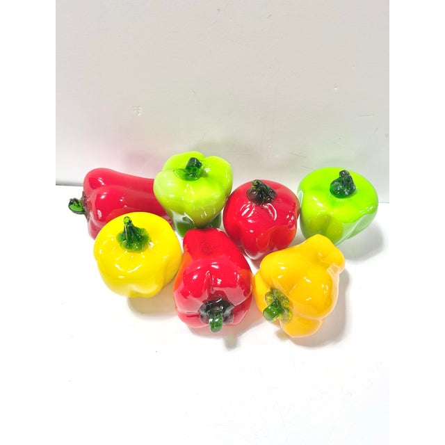 A vibrant set of vintage Murano-style blown art glass bell peppers in bright red, yellow, and green with applied green...