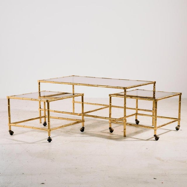 An Italian brass coffee table with a bamboo-like structure from the 1970s. The coffee table includes two smaller side...