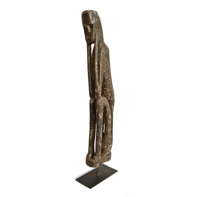 Old carved wood tribal figure from north India. Beautiful elegant form and characteristic aged patina. Displayed on iron...