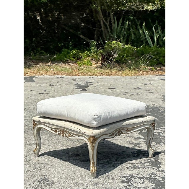 Infuse your interior with timeless elegance using this vintage Regency cane ottoman. Featuring an ornate carved wood frame...