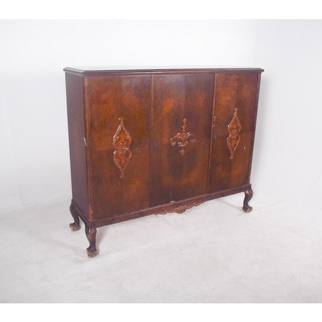 Sideboard with three doors. In dark wood, with shelves inside, it has a sturdy, symmetrical structure, with three front...