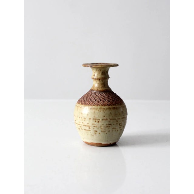 This is a vintage studio pottery bottleneck vase in hand-thrown ceramic with a warm cream glaze and soft rose pink...